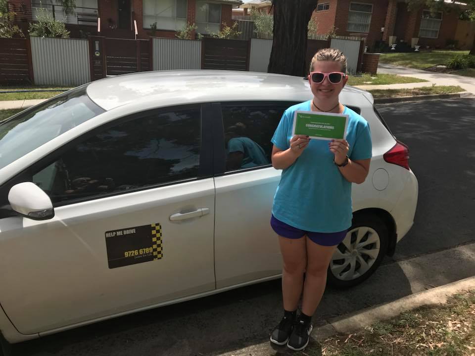 Student with congratulations card next to instructor car
