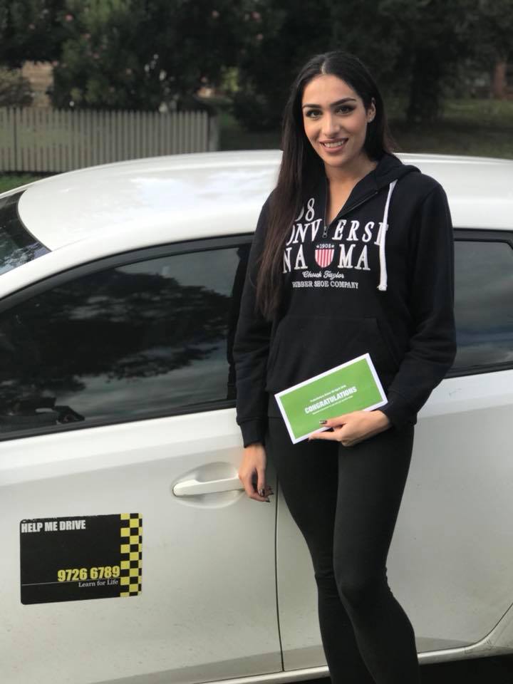 Student with congratulations certificate next to HELP ME DRIVE car